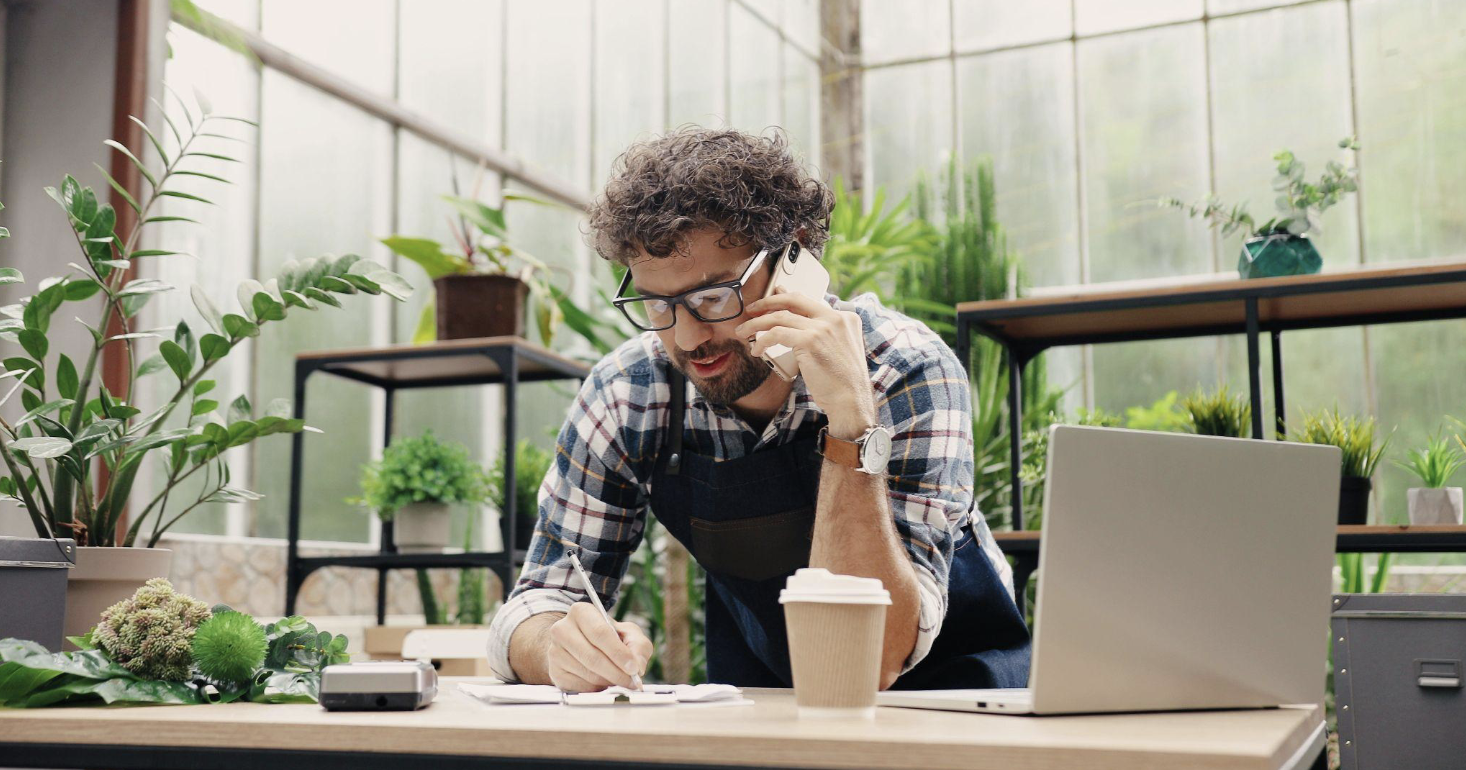 business man talking on the phone with plants behind him